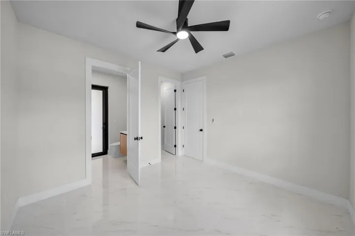 Unfurnished bedroom with a ceiling fan, baseboards, visible vents, and marble finish floor