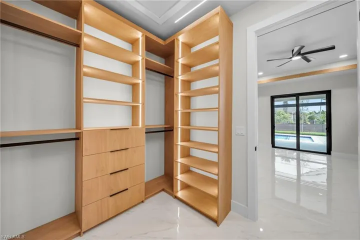 Spacious closet with ceiling fan and marble finish floor