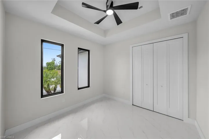 Unfurnished bedroom featuring visible vents, a raised ceiling, marble finish floor, and baseboards