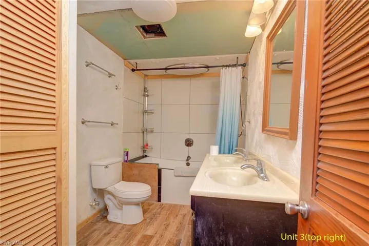 Full bathroom with a closet, shower / bath combination with curtain, light wood-style flooring, and double vanity