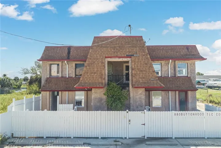 View of front of property with roof with shingles, mansard roof, a gate, and a fenced front yard