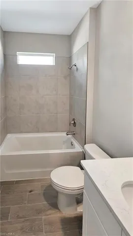 Full bathroom featuring vanity, tiled shower / bath combo, and toilet