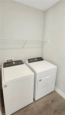 Clothes washing area featuring separate washer and dryer and hardwood / wood-style flooring
