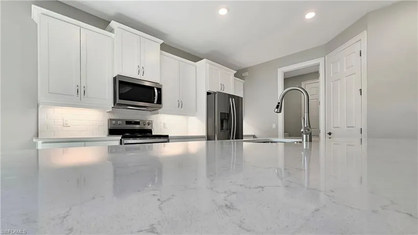 Kitchen featuring white cabinets, sink, backsplash, and stainless steel appliances