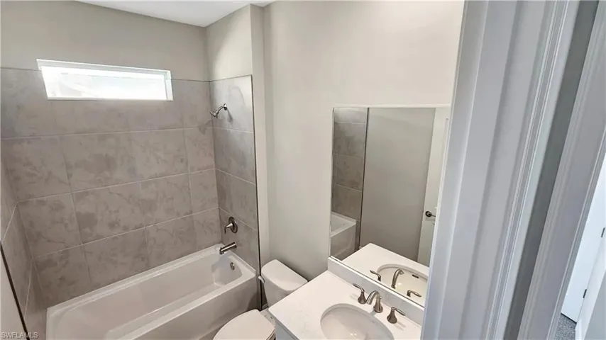 Full bathroom featuring toilet, tiled shower / bath combo, and vanity