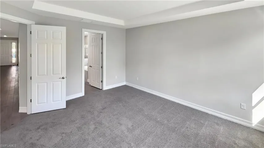 Unfurnished bedroom with a tray ceiling and dark colored carpet