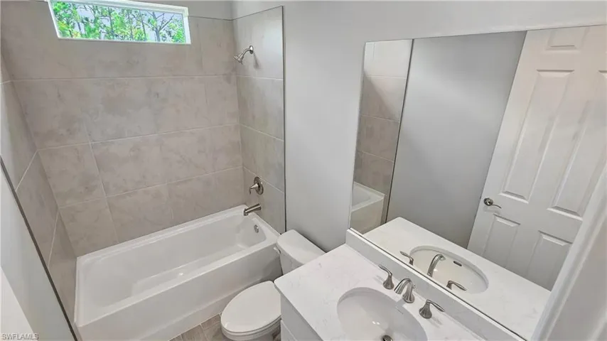 Full bathroom with toilet, vanity, and tiled shower / bath