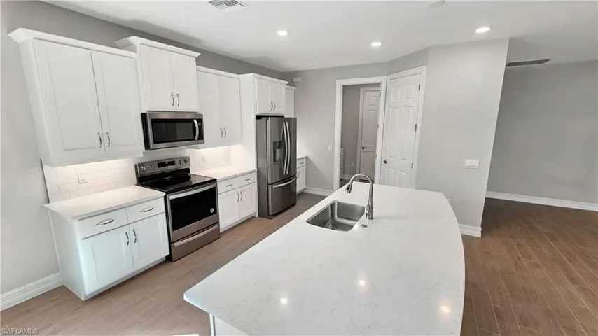 Kitchen featuring sink, backsplash, light stone countertops, and stainless steel appliances