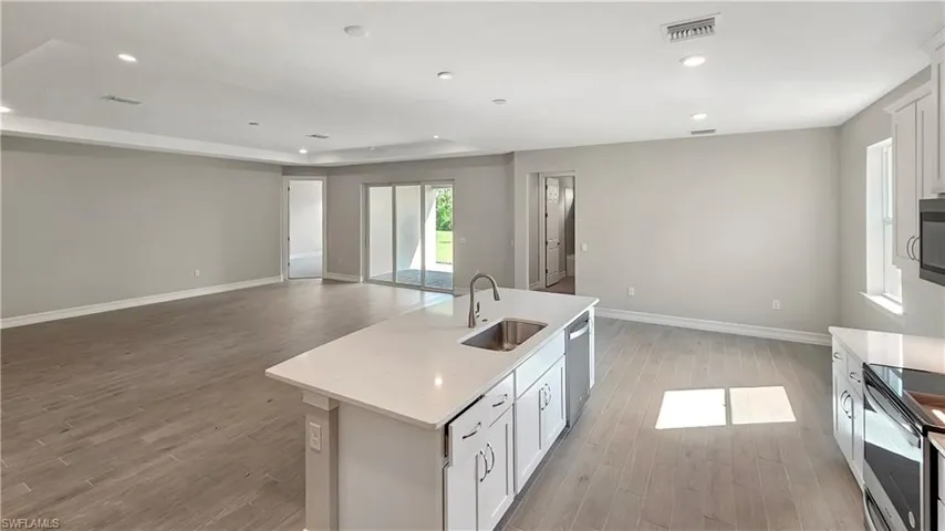 Kitchen featuring white cabinets, sink, light hardwood / wood-style flooring, and an island with sink