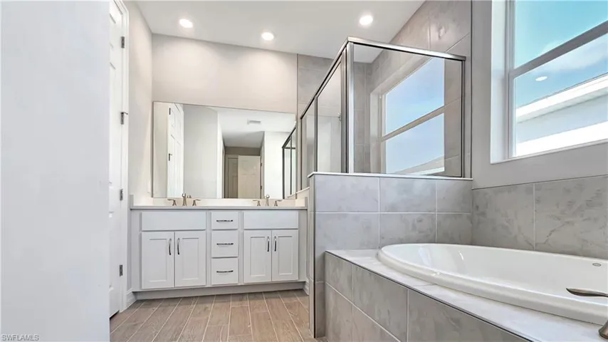 Bathroom with hardwood / wood-style flooring, independent shower and bath, and double vanity