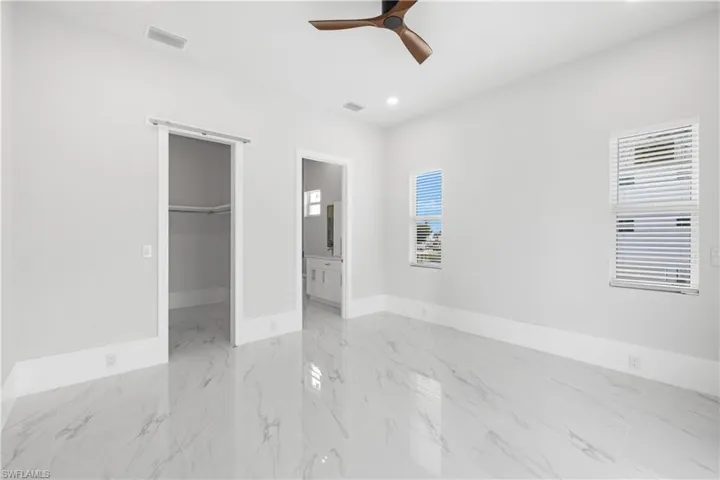 Unfurnished bedroom with a spacious closet, ceiling fan, recessed lighting, and ensuite bathroom