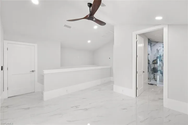 Empty room featuring recessed lighting, a ceiling fan, lofted ceiling, and light marble finish flooring