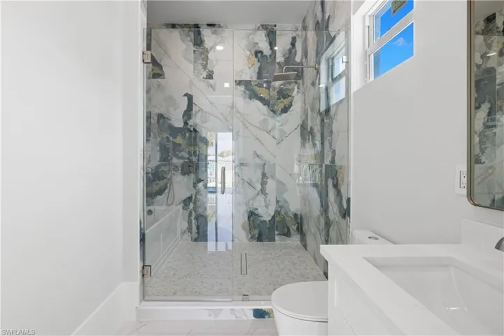 Full bath featuring a marble finish shower, plenty of natural light, and vanity