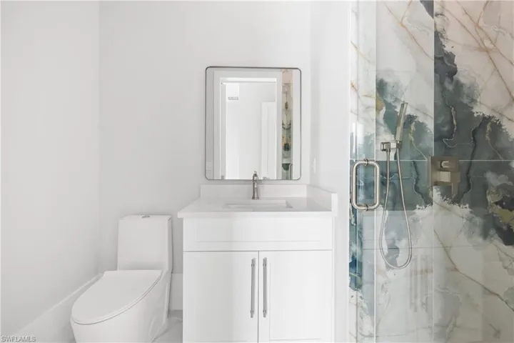 Full bathroom featuring a marble finish shower and vanity