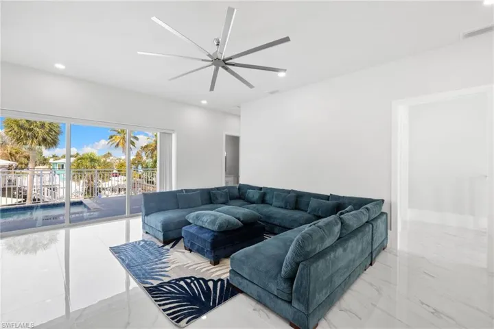 Living room featuring ceiling fan, recessed lighting, and light marble finish floors