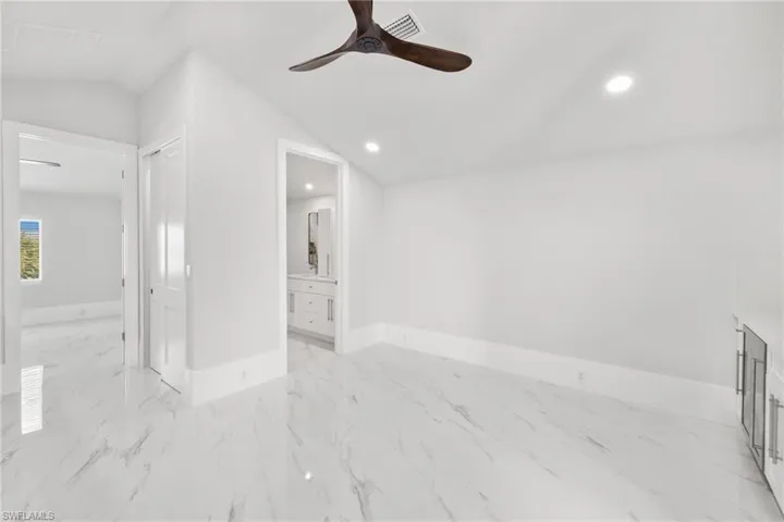 Spare room featuring ceiling fan, light marble finish flooring, recessed lighting, and vaulted ceiling