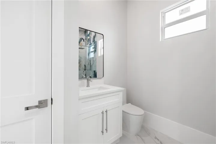Half bathroom with vanity and light marble finish floors