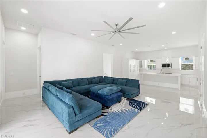 Living area with ceiling fan, recessed lighting, and light marble finish flooring