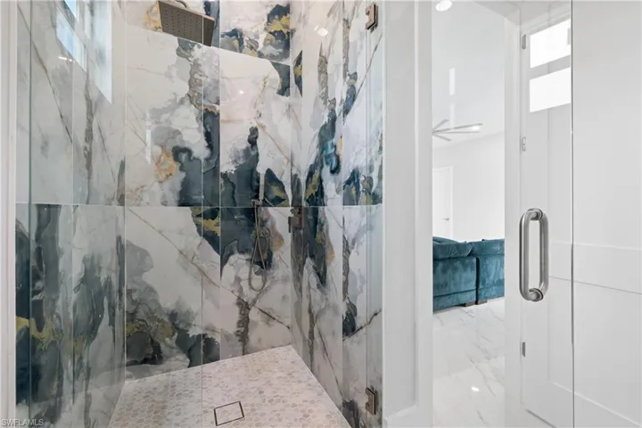 Bathroom featuring a marble finish shower and light marble finish floors