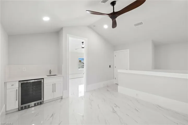Indoor wet bar featuring wine cooler, white cabinets, a ceiling fan, recessed lighting, and light stone counters