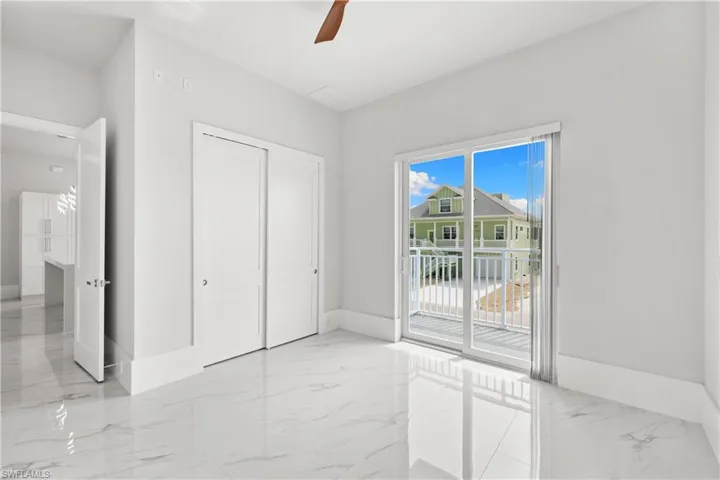 Unfurnished bedroom featuring light marble finish floors, a closet, access to exterior, and a ceiling fan