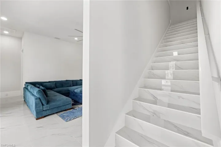 Stairs featuring marble look tiles and recessed lighting