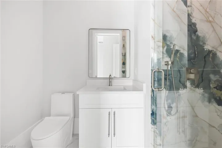 Full bath featuring a marble finish shower and vanity