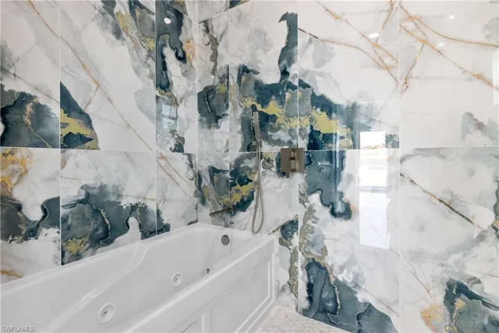 Bathroom with a tub with jets and a marble finish shower