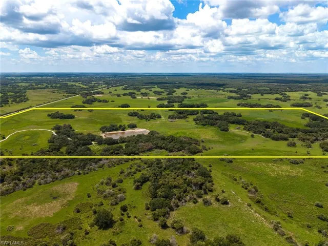 Expansive land parcel featuring a natural pond, abundant mature trees, and open green spaces