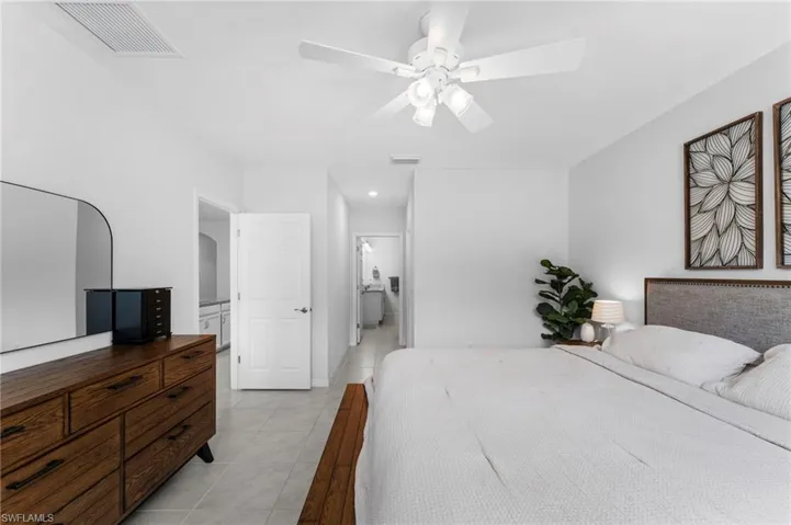 Tiled bedroom featuring ceiling fan and ensuite bath