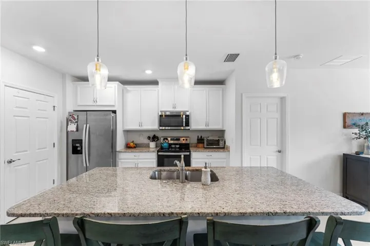 Kitchen featuring hanging light fixtures, an island with sink, and stainless steel appliances