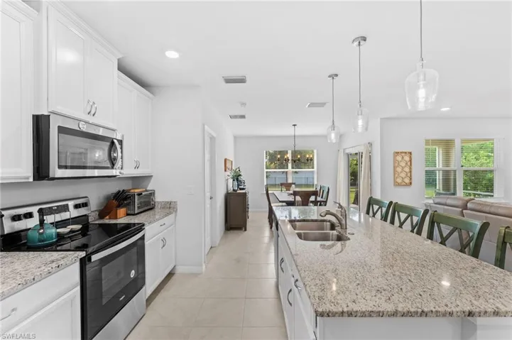 Kitchen featuring light tile patterned floors, stainless steel appliances, and a kitchen island with sink