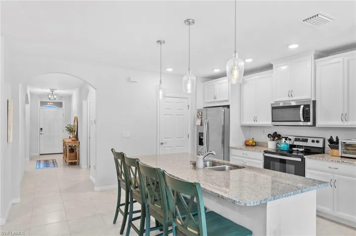 Kitchen featuring light tile patterned flooring, a kitchen island with sink, white cabinetry, and stainless steel appliances