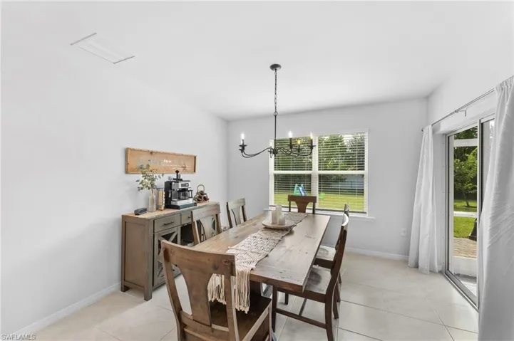 Dining area with light tile patterned flooring and an inviting chandelier