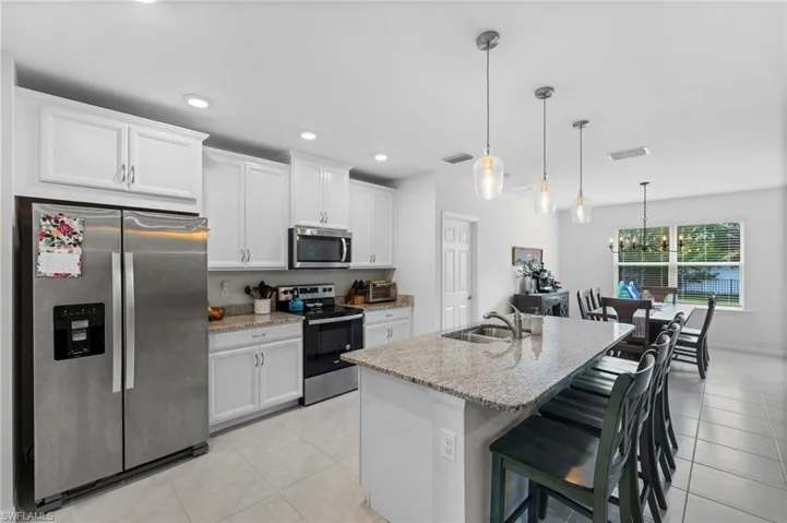 Kitchen featuring sink, appliances with stainless steel finishes, light stone countertops, and light tile patterned floors
