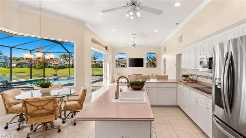 Open-concept kitchen featuring white cabinetry, stainless steel appliances, and a central island with a sink
