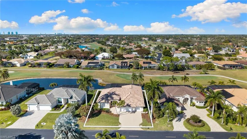Aerial perspective of suburban area with a golf course and a nearby body of water