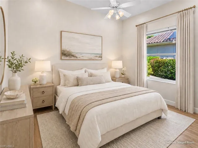 Bedroom featuring vaulted ceilings, wood-finish flooring, a window with exterior landscaping, and a ceiling fan with integrated lighting