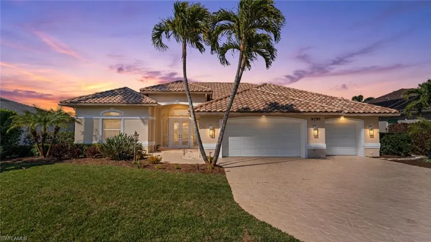 Mediterranean-style residence featuring a tile roof, stucco exterior, and an expansive paver driveway