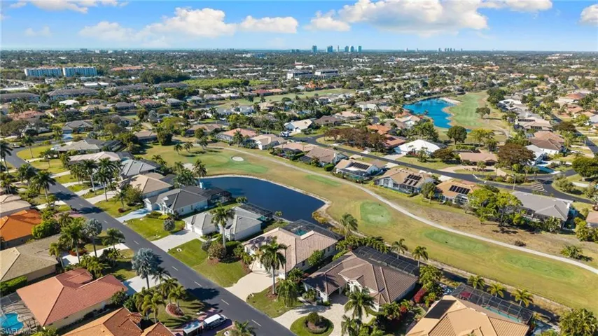 View of urban area featuring a nearby body of water, a golf course, and nearby suburban area