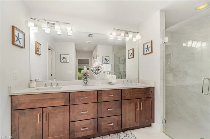 Bathroom featuring double vanity, a shower stall, and light tile patterned flooring