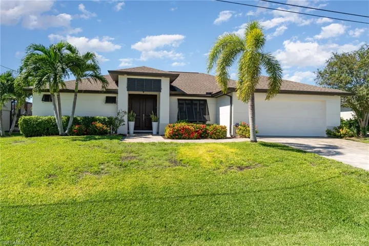 View of front of house featuring an attached garage, driveway, a front yard, and stucco siding