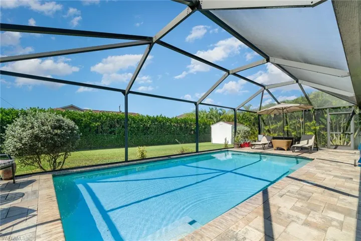 Outdoor pool with a lanai, a storage shed, a sunroom, a patio, and a lawn