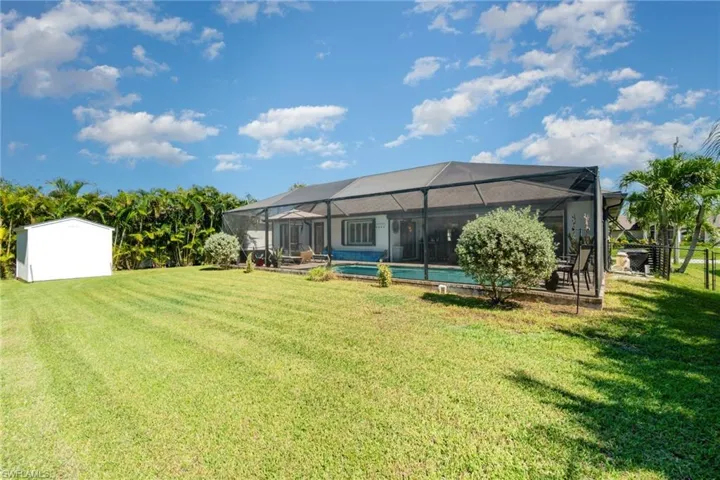Back of property featuring a sunroom, an outdoor pool, a lawn, and glass enclosure