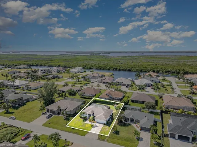 Aerial view of residential area featuring a nearby body of water and property parcel outlined