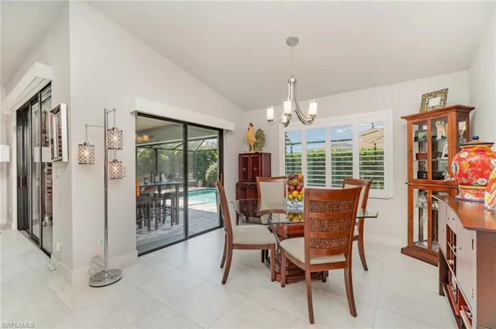 Dining area with a chandelier, vaulted ceiling, and light tile patterned floors