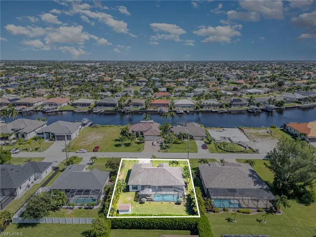 Aerial perspective of suburban area with property parcel outlined and a nearby body of water