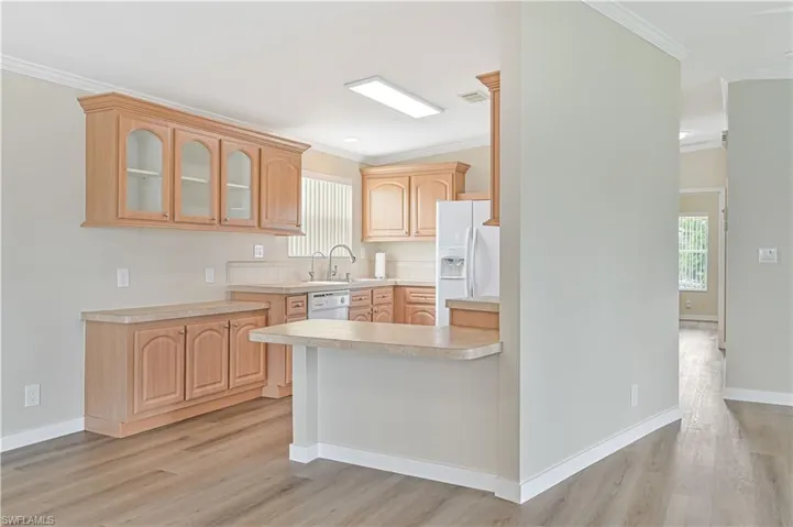 Kitchen with plenty of natural light, light brown cabinetry, and white appliances