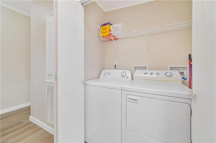 Laundry area with washing machine and dryer, ornamental molding, and light hardwood / wood-style floors