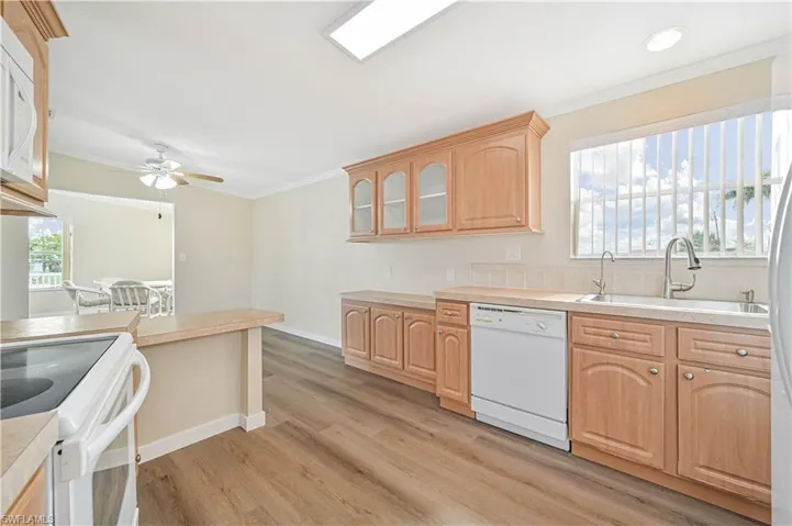 Kitchen with white appliances, crown molding, sink, ceiling fan, and light wood-type flooring